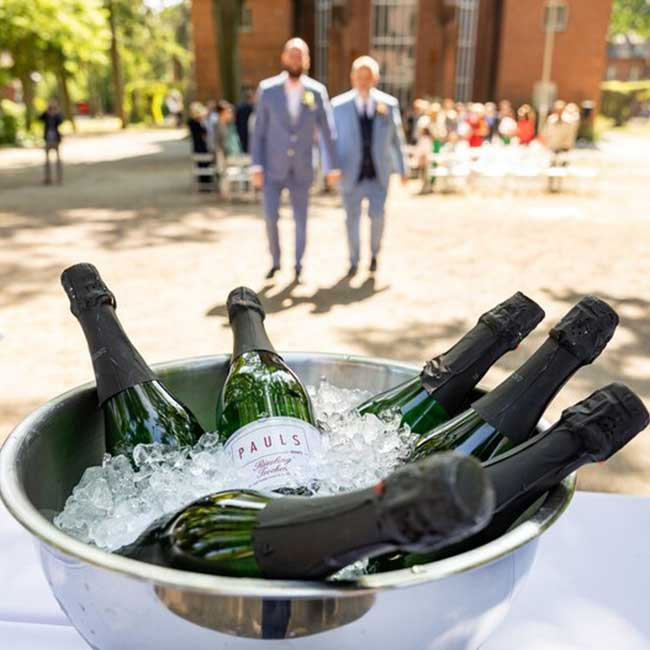 Hochzeitspaar im Hintergrund, im Vordergrund Sektflaschen