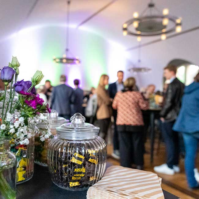Eventlocation mit sprechenden Menschen und netter Deko im Vordergrund