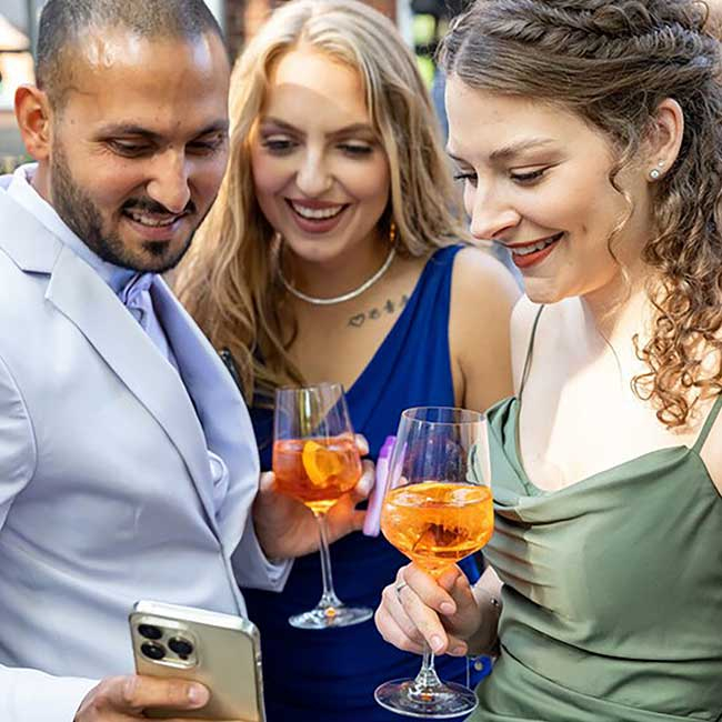 Partygäste schauen gemeinsam auf ein Smartphone